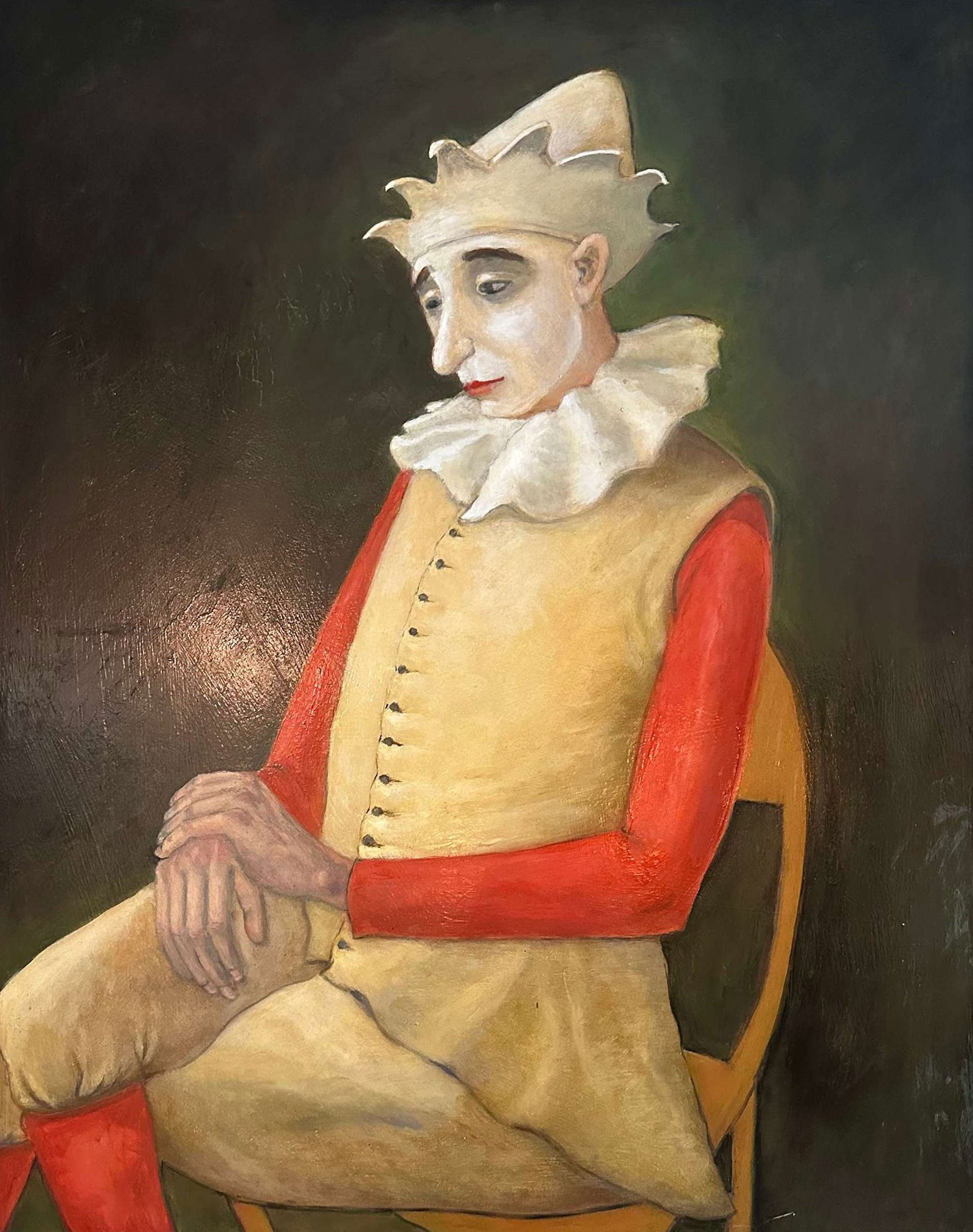 Sad clown in old-fashioned costume sitting on chair with crossed legs and hands on knee