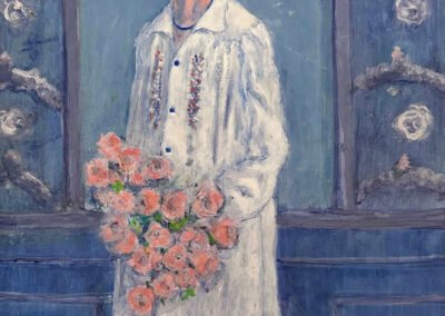 Portrait of Katherine Mathie Burns with a white hat standing in front of an ornate wall and holding a bouquet of flowers